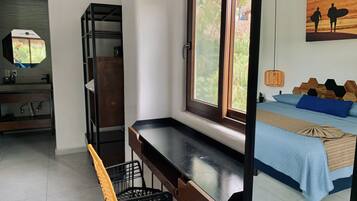 Une chambre à coucher avec un lit, un bureau, une chaise, une fenêtre et un tableau accroché au mur.