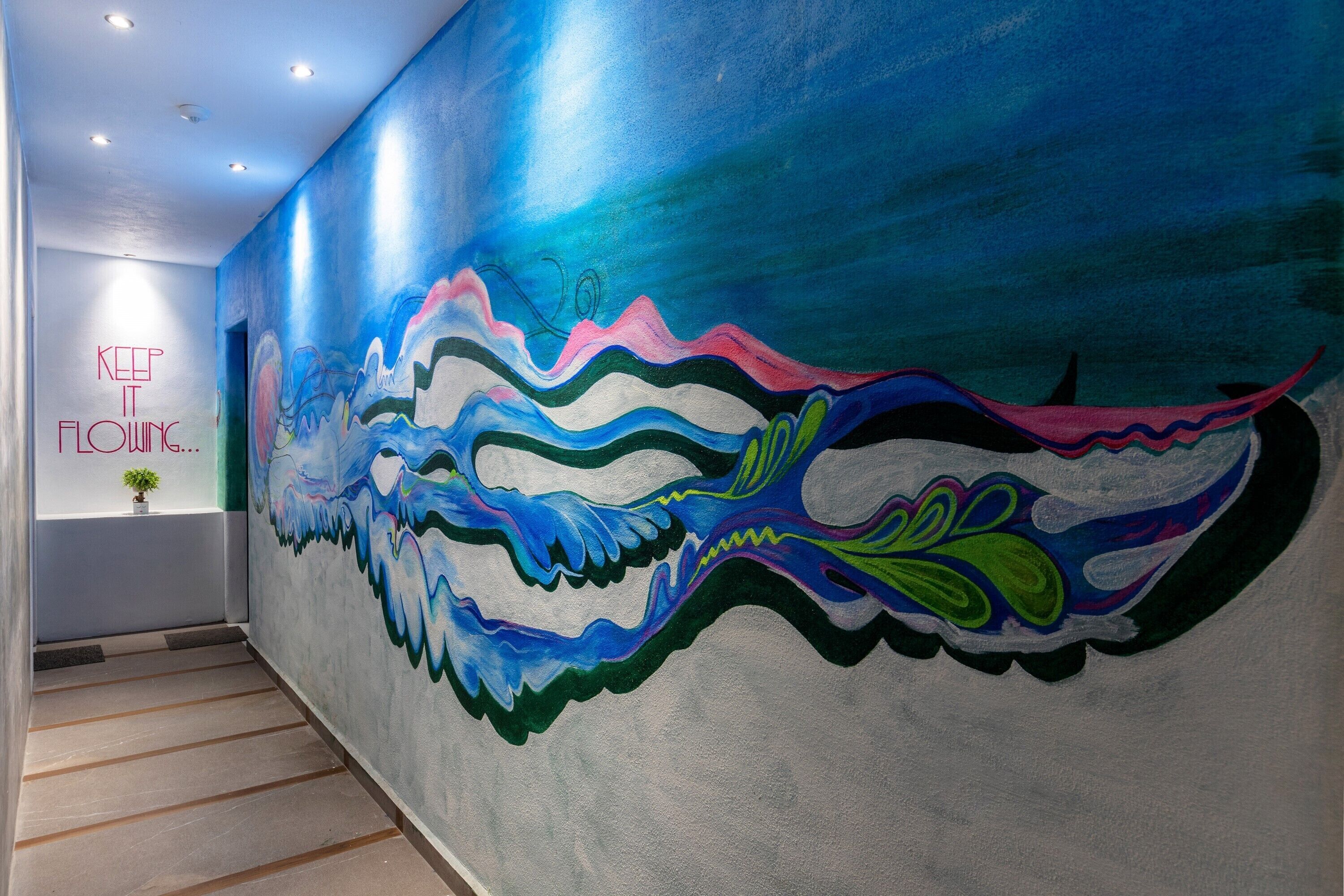 A hallway with a colorful mural on the wall and a sign that reads "KEEP IT FLOWING."