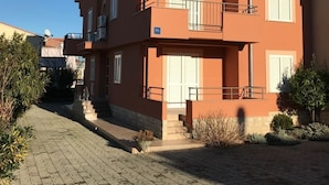 A multi-story building with a red facade, balconies, and a paved walkway. - Apartment in Sukošan with Balcony, Air condition, WIFI (4941-5) (Sukošan)