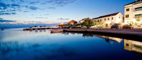 A waterfront scene with calm water reflecting buildings and boats.