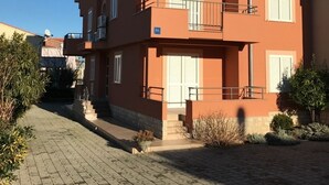 Un immeuble à plusieurs étages, doté d’une façade rouge, de balcons et d’une allée pavée.