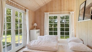 Une chambre à coucher avec un grand lit, deux fenêtres et une petite table de chevet avec une lampe.