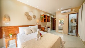 A hotel room with a wooden headboard, a bed with white linens, a bedside table with a lamp, a small plant, and a mirror on the wall. - Pousada Som dos Passaros (Ipojuca)