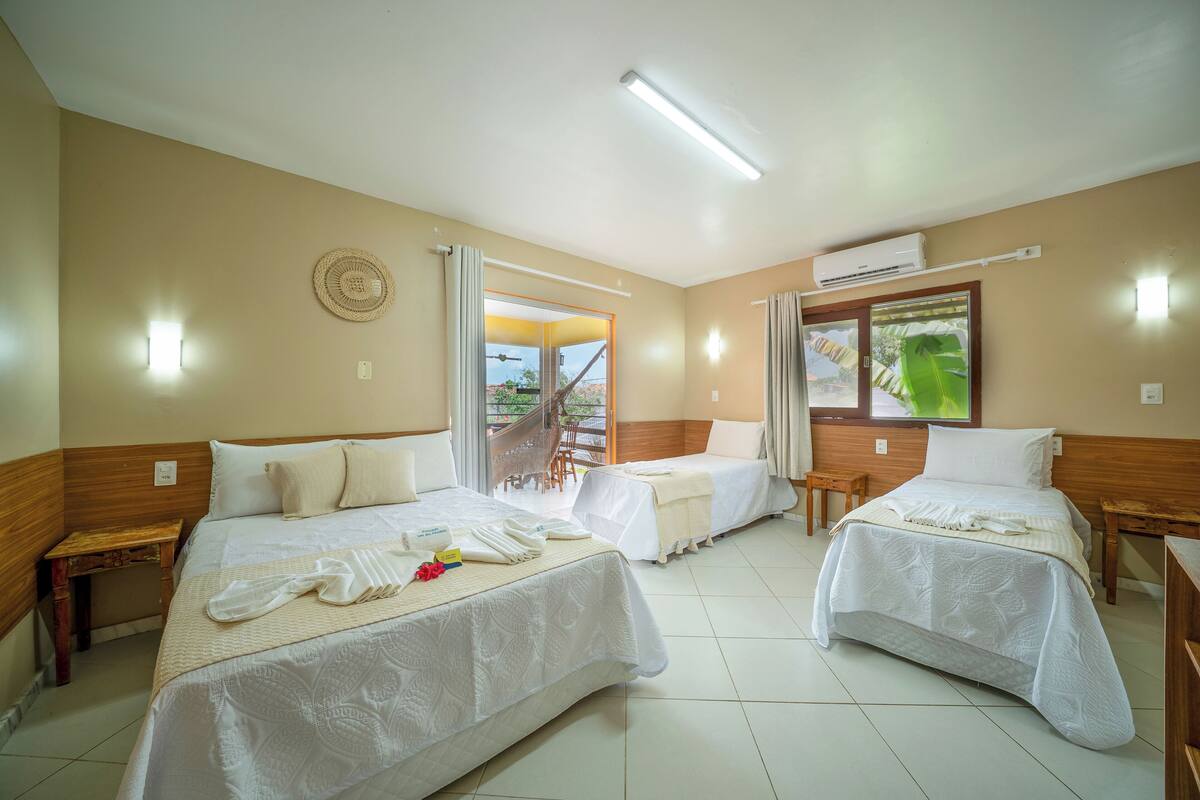 Une chambre d’hôtel avec deux lits, une tête de lit en bois, un balcon avec vue et un appareil de climatisation.