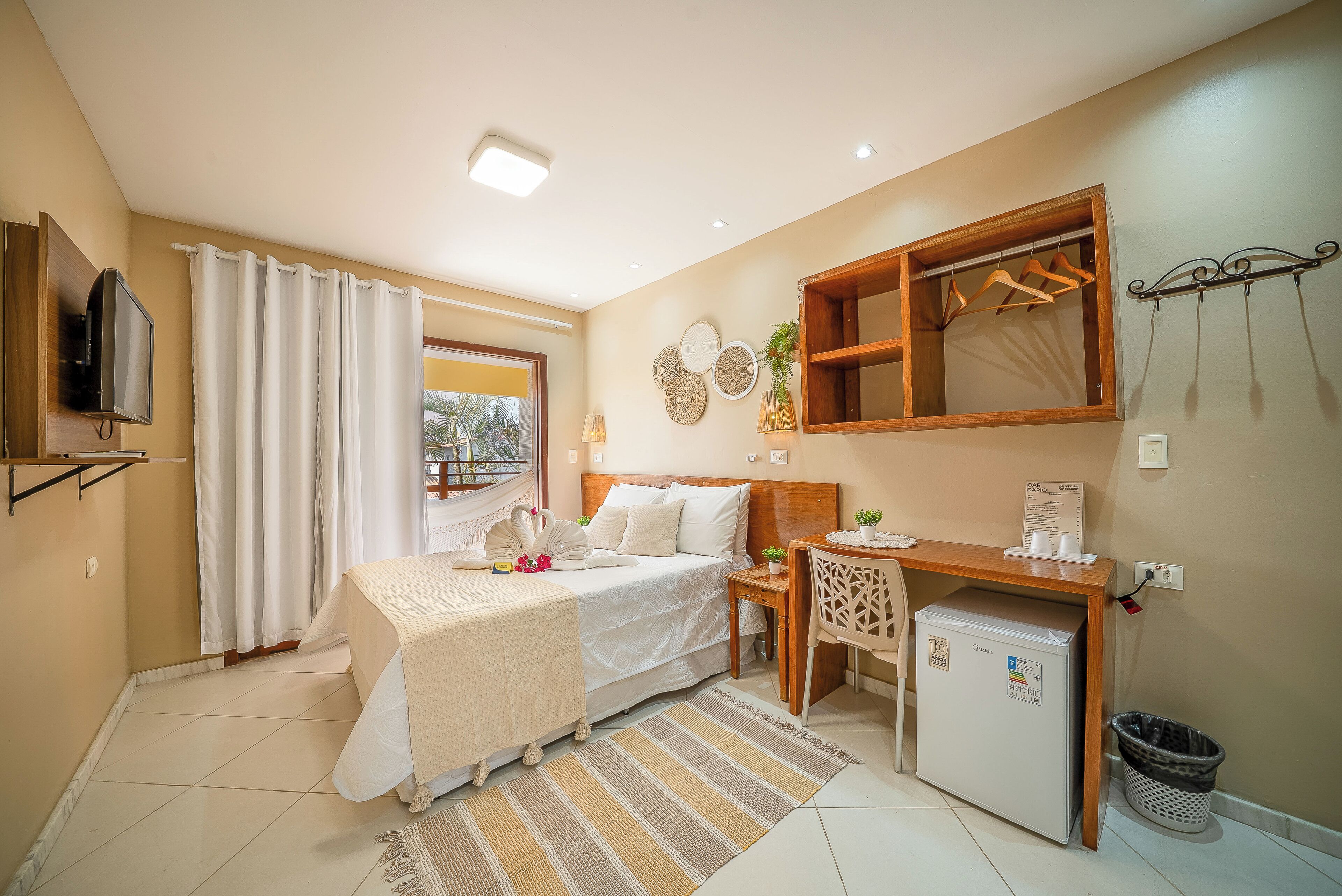 A hotel room with a bed, desk, and a small refrigerator.