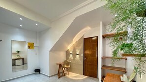 A modern interior with a wooden dining table, a small seating area, and a staircase leading to an upper level. - Pousada Som dos Passaros (Ipojuca)