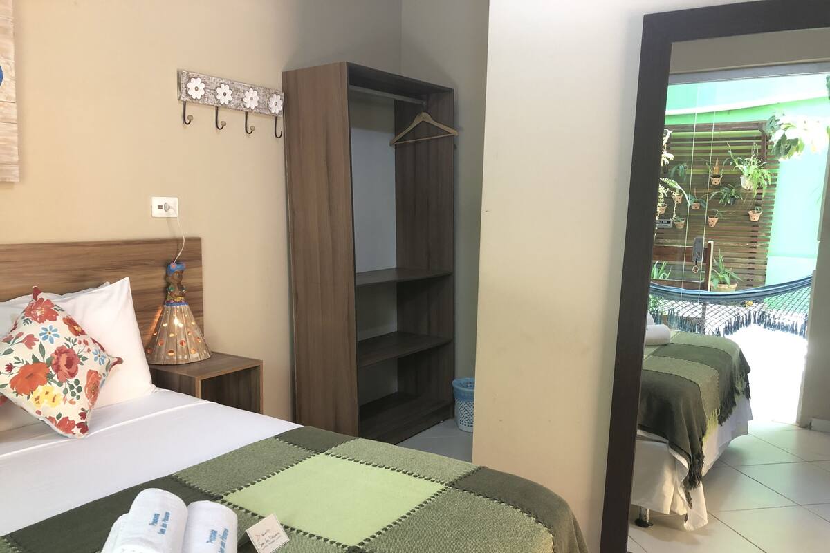 Une chambre d’hôtel avec un lit, une armoire, une plante suspendue et une vue sur l’extérieur.
