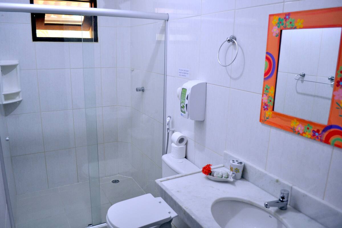 Une salle de bain équipée d’une douche, de toilettes, d’un lavabo et d’un miroir avec un cadre coloré.