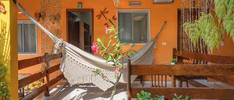 A hammock, wooden furniture, and potted plants in a room with orange walls and a wooden ceiling.