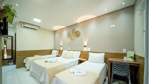 A hotel room with three beds, a desk, a chair, and a wall-mounted air conditioner. - Pousada Som dos Passaros (Ipojuca)