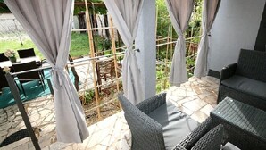 Una zona relax all'aperto con mobili in vimini e tende.
