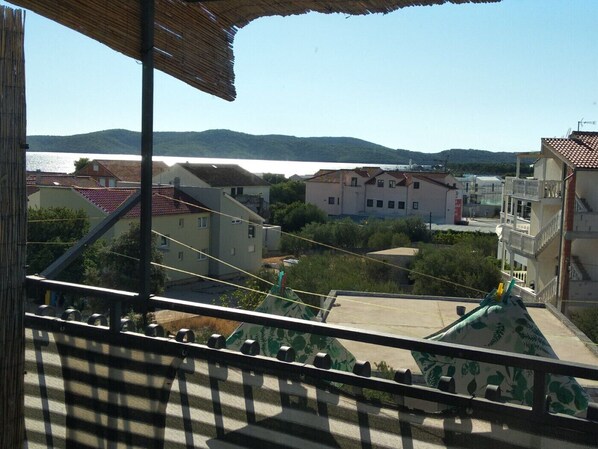 A balcony with a view of a body of water, buildings, and hills in the distance.
