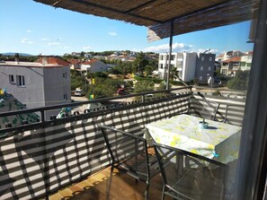 Ein Balkon mit Tisch und Stühlen mit Blick auf eine Wohngegend mit Häusern und Grünflächen.