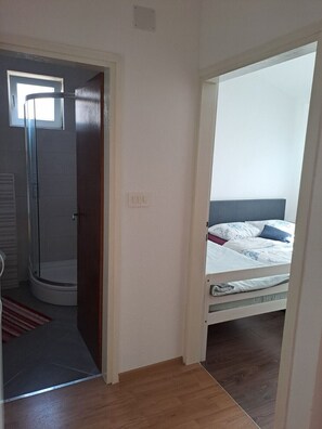 Ein Schlafzimmer mit Bett, Dusche und einer Tür zu einem anderen Raum.