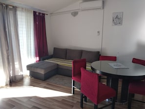 En moderne stue med en hjørnesofa, et rundt spisebord med stole og en lille måtte.