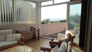 Un ampio balcone con vista sul mare, arredato con divano, sedie e tavolo.