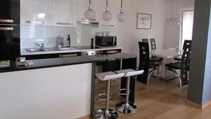 Una cucina moderna con mobili bianchi, un piano di lavoro nero e un'area pranzo con tavolo e sedie.