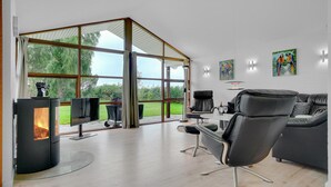 En moderne stue med glasvæg, pejs, spiseplads og sofa.