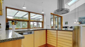 Et moderne køkken med stort vindue, granitbordplade, træskabe og stålgrejs.