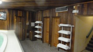 A bathroom with wooden walls, a tiled floor, and shelves with towels. - Ski In Ski Out Condo (Whitefish)