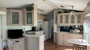 A compact kitchen with a central island, built-in microwave, and a dining area with a table and chairs. - Grand Oaks Resort (Lady Lake)
