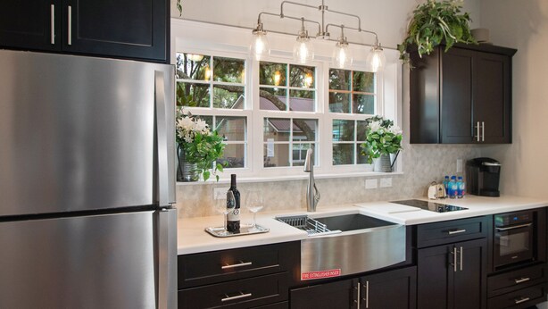 A modern kitchen with dark cabinetry, a stainless steel refrigerator, a double sink, and a built-in oven. - Grand Oaks Resort (Lady Lake)