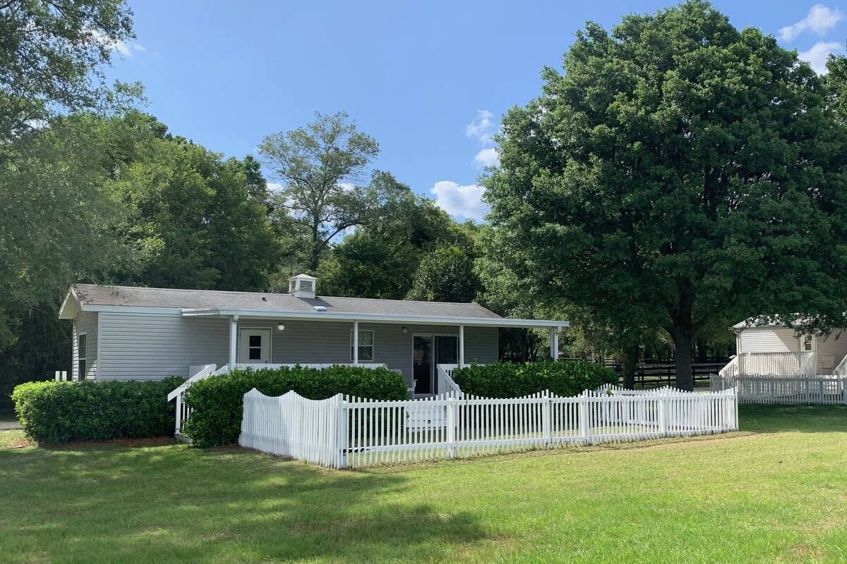 A single-story house with a white exterior, a front porch, and a white picket fence.