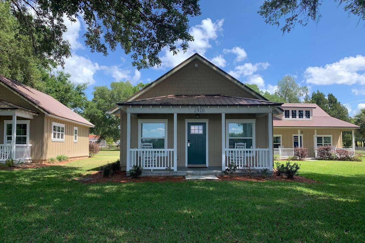 A single-story house with a front porch, a green door, and a number 2920 on the front.