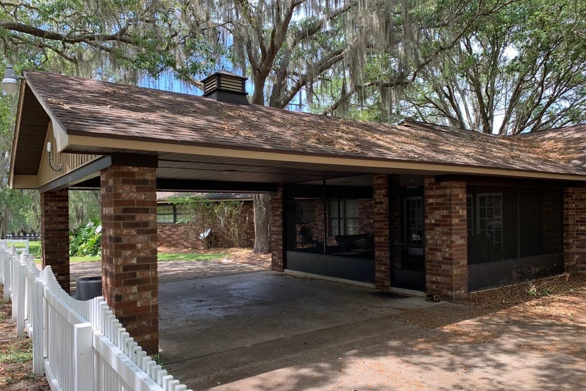 A covered outdoor area with brick pillars and a roof, surrounded by a white fence.