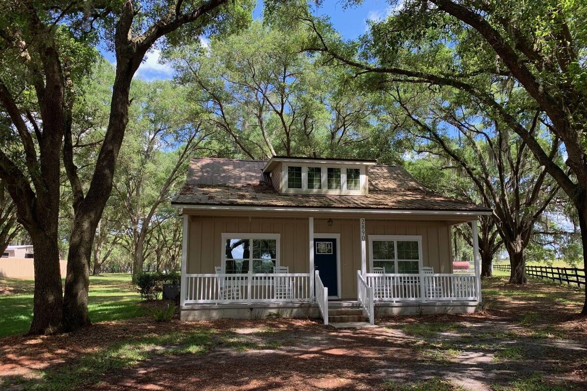 A small, single-story house with a front porch and a dark blue door.