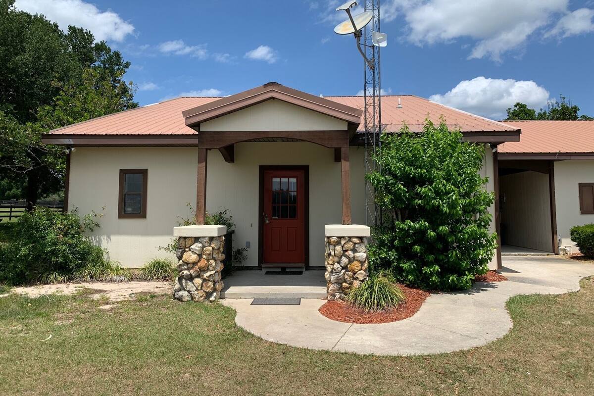 A single-story house with a red door, a stone pillar, and a satellite dish.