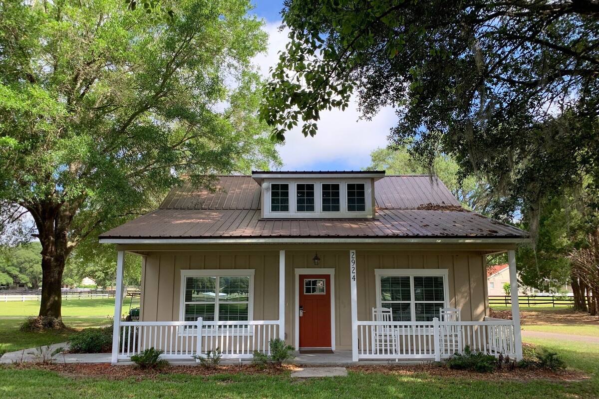 A single-story house with a red door, white porch, and a number '2924' on the wall.