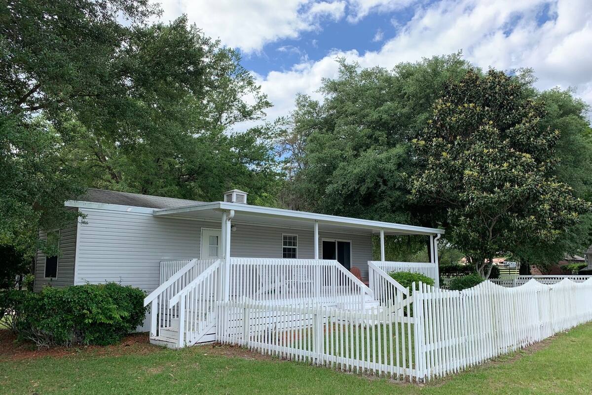 A single-story white house with a porch and a white picket fence.