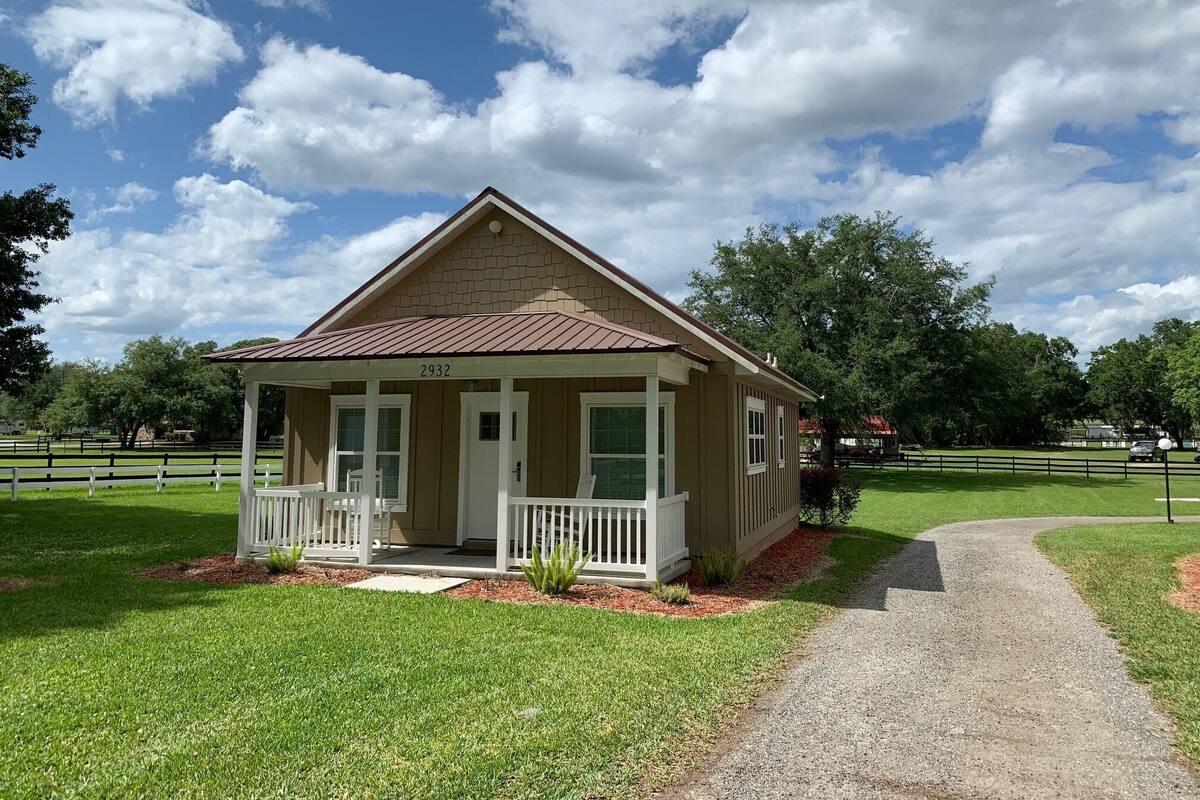 A single-story house with a gabled roof, numbered 2932, featuring a front porch with white railings and a small garden area.