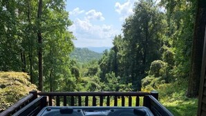 A hot tub with a wooden deck and a view of a forested valley. - Pet-Friendly,Cedar Cabin, Spa Tub, WiFi,Fireplace (Ferguson)