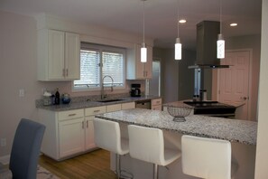 A modern kitchen with white cabinets, granite countertops, and pendant lighting.