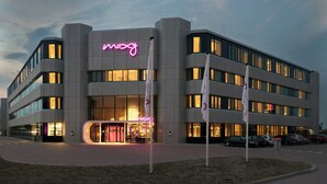 Un bâtiment moderne avec une enseigne au néon indiquant le mot « mozy » et de nombreuses fenêtres.
