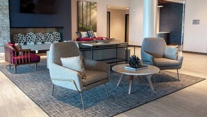 Een moderne lounge met zitplaatsen, een open haard en een televisie.