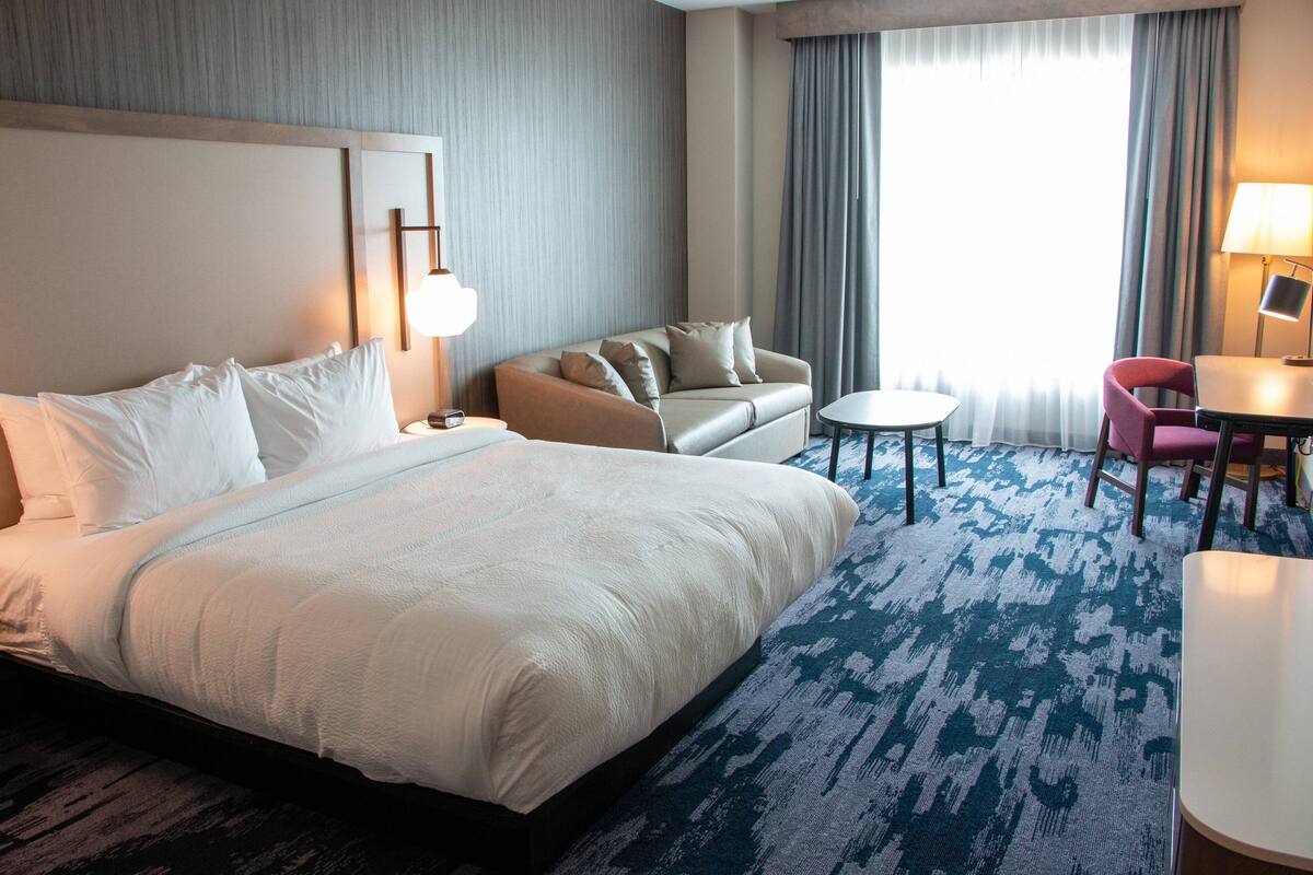 Een hotelkamer met een groot bed, een bank, een bijzettafeltje en een stoel.