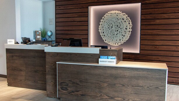 Een receptiebalie met een houten afwerking, een digitaal scherm en een bord met de naam 'Marriott Bonvoy'.