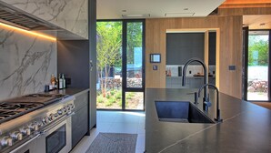 Une cuisine moderne dotée d’une cuisinière à gaz, d’appareils électroménagers en acier inoxydable et d’un grand îlot central avec un évier.