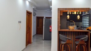 Een moderne keuken met een houten bar, twee barkrukken en hanglampen.