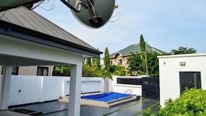 Een dakzwembad met een schotelantenne, een overdekte zithoek en uitzicht op omliggende gebouwen.