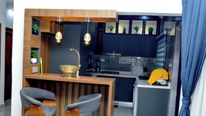 Een kleine keuken met een bar, houten krukken en moderne verlichtingsarmaturen.