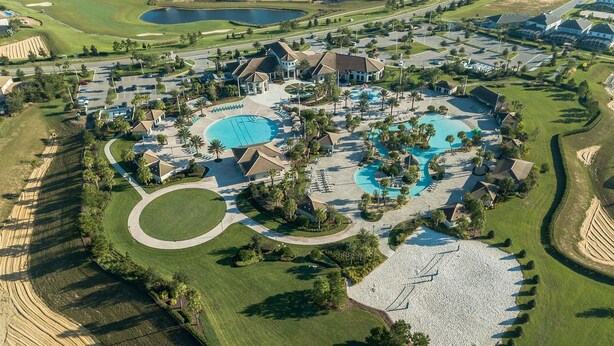 An aerial view of a golf resort with multiple swimming pools, well-maintained lawns, and residential buildings. - 1433rf- The Retreat at Championsgate (Davenport)
