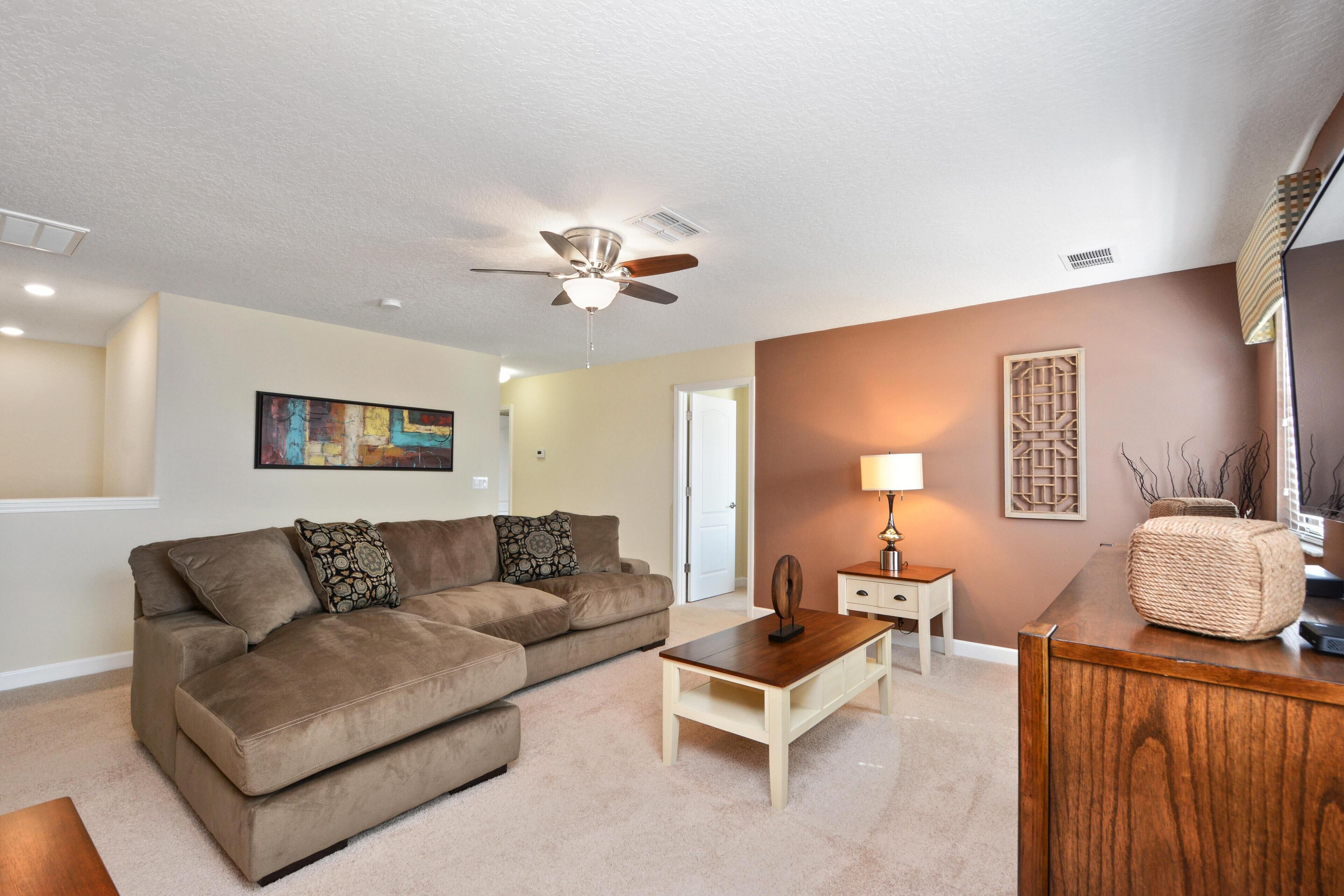 A living room with a brown sofa, a wooden coffee table, and a ceiling fan.