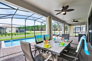 A covered patio with a pool, outdoor seating, and ceiling fans.