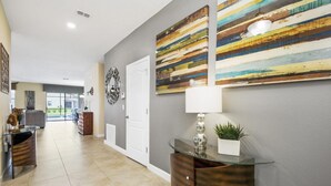 A hallway with a glass-top console table, a potted plant, and a decorative mirror. - 1461rf - NON Renting 1/5/2022 The Retreat at Championsgate (Davenport)