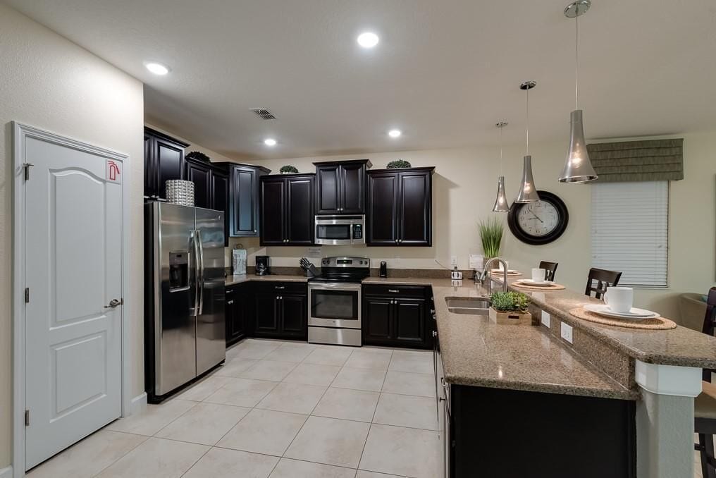 A modern kitchen with dark cabinetry, stainless steel appliances, and a granite countertop.