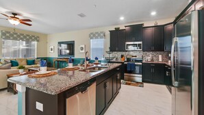 A modern kitchen with dark cabinetry, stainless steel appliances, and a granite countertop. - 1542mvd-the Retreat at Champions Gate (Davenport)